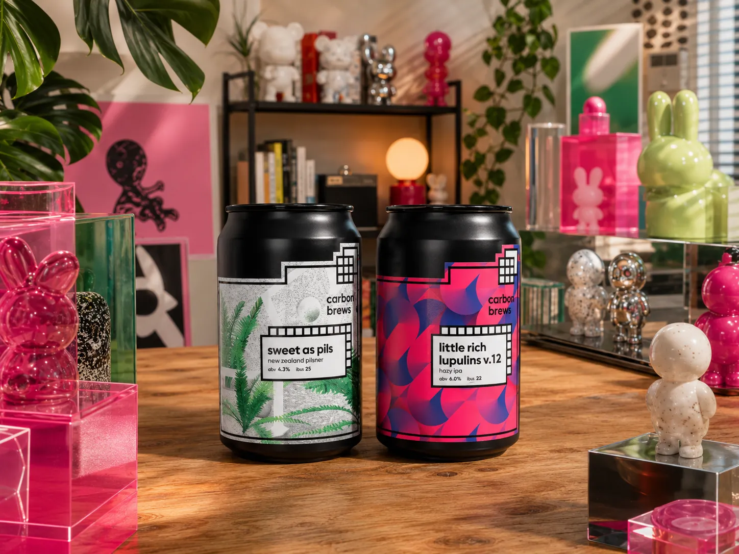 Carbon Brews Sweet As Pils and Little Rich Lupulins v.12 cans shown fully in a colorful studio scene