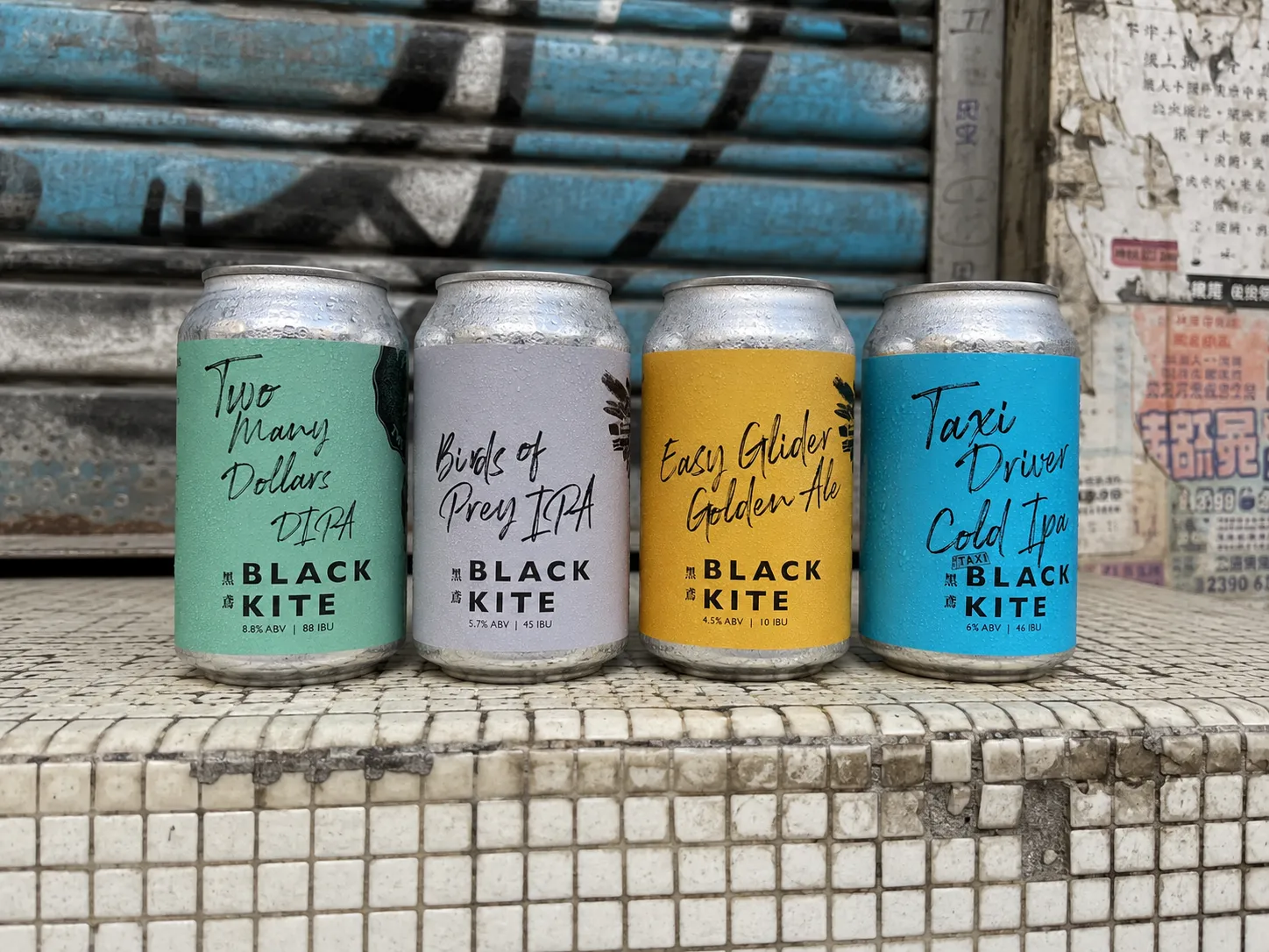 Black Kite four-can craft beer series shown fully on a tiled city ledge