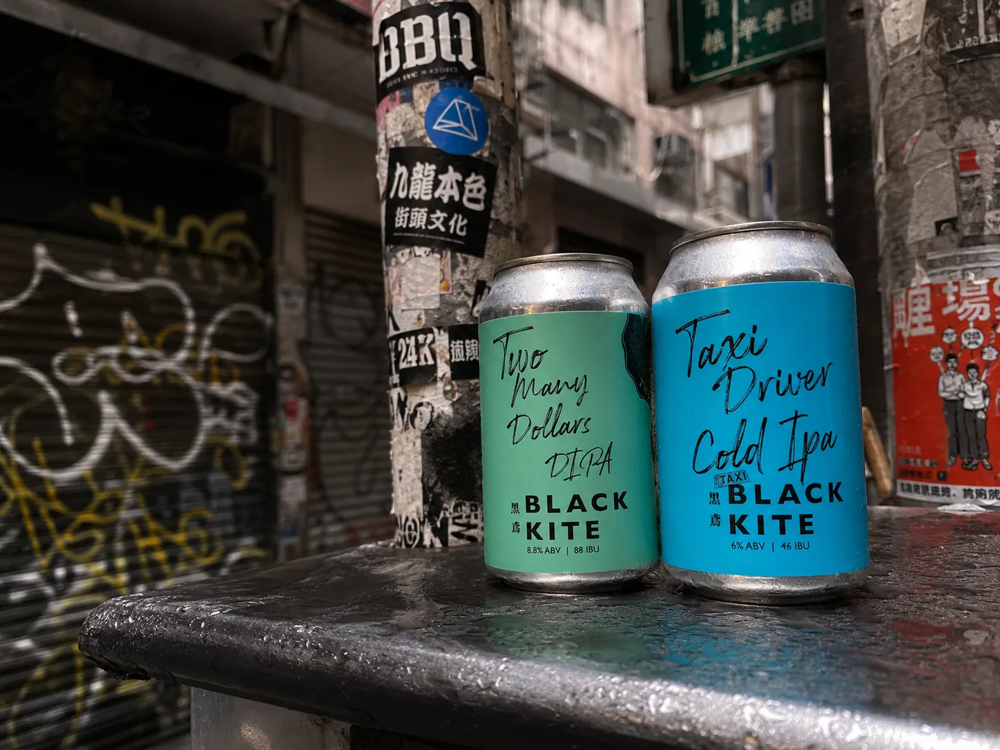 Black Kite Two Many Dollars and Taxi Driver cans shown together in a street scene