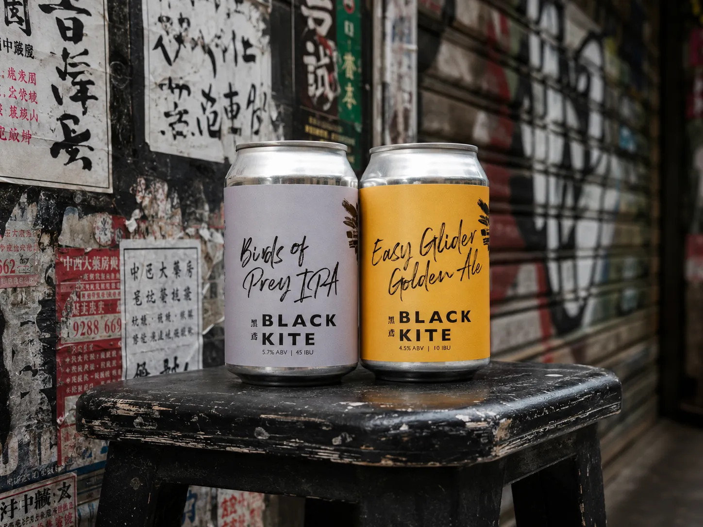 Black Kite Birds of Prey and Easy Glider cans shown together on a worn city stool